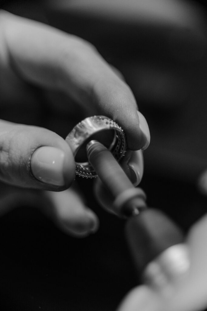Detailed black and white photo of an artisan polishing a ring with precision tools.
